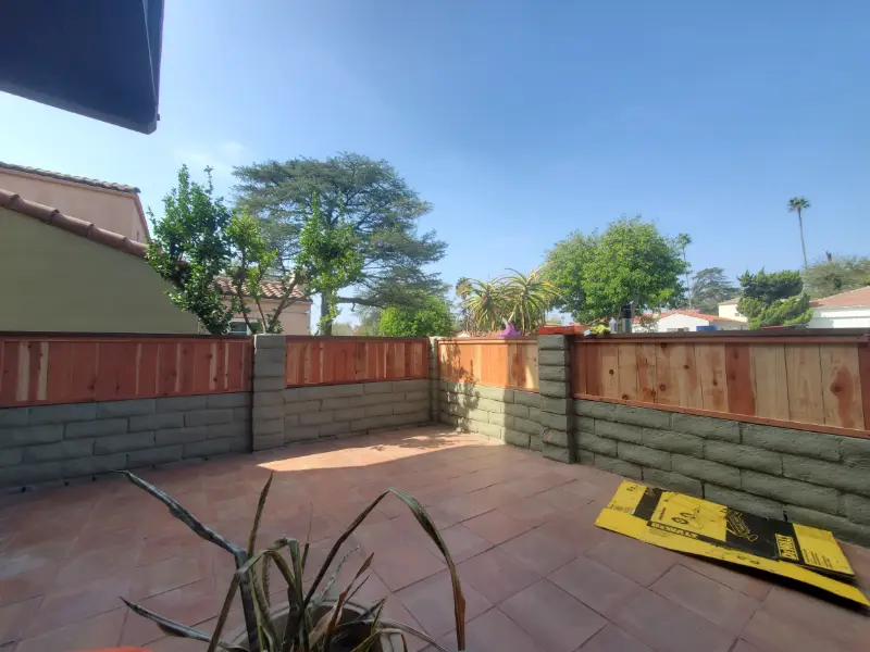 Paved backyard patio bordered by a new wood fence and planting
